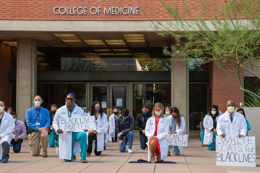 UA healthcare workers and faculty kneeling in front of the College of Medicine's building entrance. Courtesy Dr. Taylor Riall.